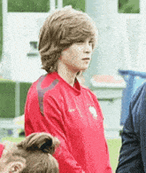 a young boy wearing a red nike sweatshirt is standing on a soccer field .