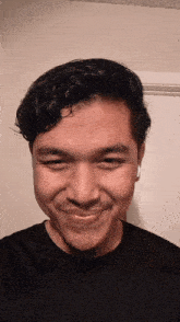 a young man wearing a black shirt and white ear buds smiles