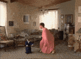 a woman in a pink dress kneeling down next to a small child