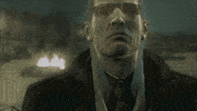 a man with long white hair and sunglasses looks at the camera