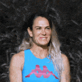 a woman wearing a blue kappa tank top smiles