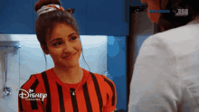 a woman in a red and black striped shirt is talking to another woman on disney channel