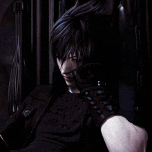 a man in a black shirt is sitting in a dark room