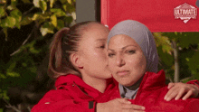 a girl kissing another girl on the cheek in front of a sign that says ultimate challenge