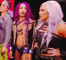 three female wrestlers are standing next to each other in a room .