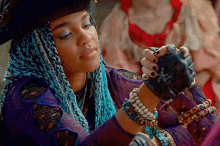 a woman with blue braids is wearing a lot of bracelets on her wrists