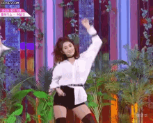 a woman in a white shirt and black shorts is dancing on a stage