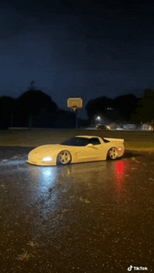 a white car is parked in the rain near a basketball hoop