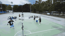 a group of people are playing a game of basketball on a court with a referee in the background