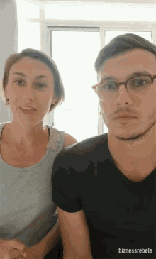a man and a woman are standing next to each other and the man has glasses