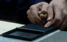 a person is holding a black box with their finger on it