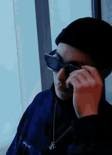 a man wearing a black hat and sunglasses is talking on a cell phone .