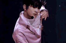 a young man is wearing a pink jacket and a microphone .