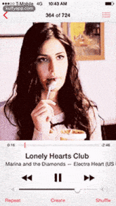 a woman is eating a spoonful of food while listening to a song called lonely hearts club