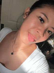 a woman wearing a white shirt and a black necklace with a four leaf clover on it