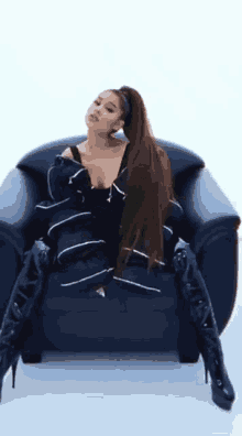 ariana grande is sitting in a chair with her legs crossed and wearing thigh high boots .