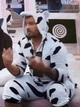 a man in a cow costume sits in front of a storm sign