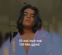 a young man with long hair is wearing a purple shirt with the words 50 mai mah mai 100 mai g @ nd written on it