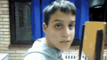 a young boy stands in front of a blue curtain