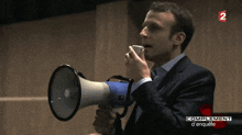 a man in a suit holds a megaphone in front of a sign that says complement d ' enquete