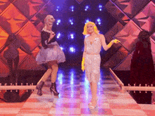two drag queens are dancing on a checkered runway