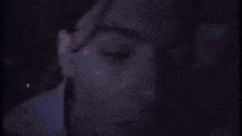a close up of a man 's face with a purple light behind him .