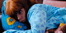 a woman with red hair is laying on a bed wearing a blue pajama set