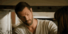 a man with a beard in a white shirt looks at a woman