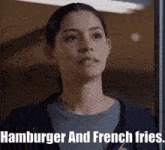 a woman says hamburger and french fries in front of a window .