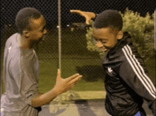 two boys are giving each other a high five while wearing adidas jackets