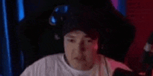 a man is wearing a hat and headphones while sitting in a chair .