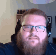 a man with a beard and glasses is wearing headphones and taking a selfie .