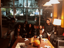 a group of people are sitting around a table with a pumpkin and a menu on it
