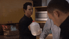 a man is holding a gallon of milk in front of a microwave