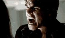 a man is screaming with his mouth wide open in a dark room .