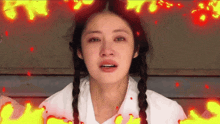 a woman with pigtails is crying and surrounded by fire