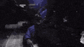 a man is laying on the floor in a dark room while a group of people are standing around him .