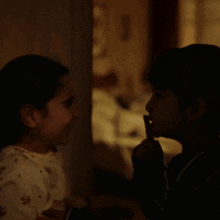 a boy and a girl looking at each other in the dark