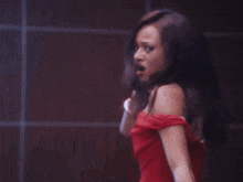a woman in a red dress is standing in front of a wall