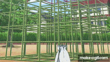 a person is standing in front of a maze made of green metal bars .