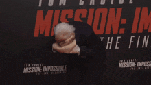 a woman is standing in front of a mission impossible sign