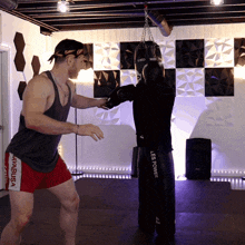 a man in a tank top and red shorts stands next to a punching bag that says lee power on it