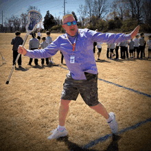 a man in a purple shirt holds a lacrosse stick in his hand
