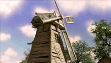 a wooden windmill with a blue sky and clouds in the background