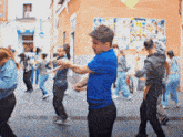 a man in a blue shirt is dancing in front of a group of people