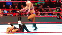 two women are wrestling in a wrestling ring with a crowd in the stands watching .