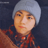 a young man wearing a beanie and a plaid shirt .