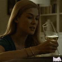a woman is pouring wine into a glass and the word kosh is on the bottom