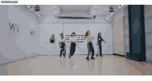 a group of girls are dancing in front of a wall that says wne on it