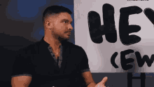 a man in a black shirt stands in front of a sign that says hey crew